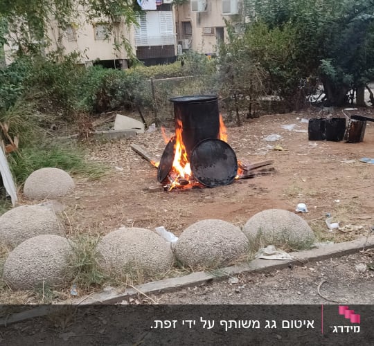 חבית מתכת בוערת עם מכסים על האש